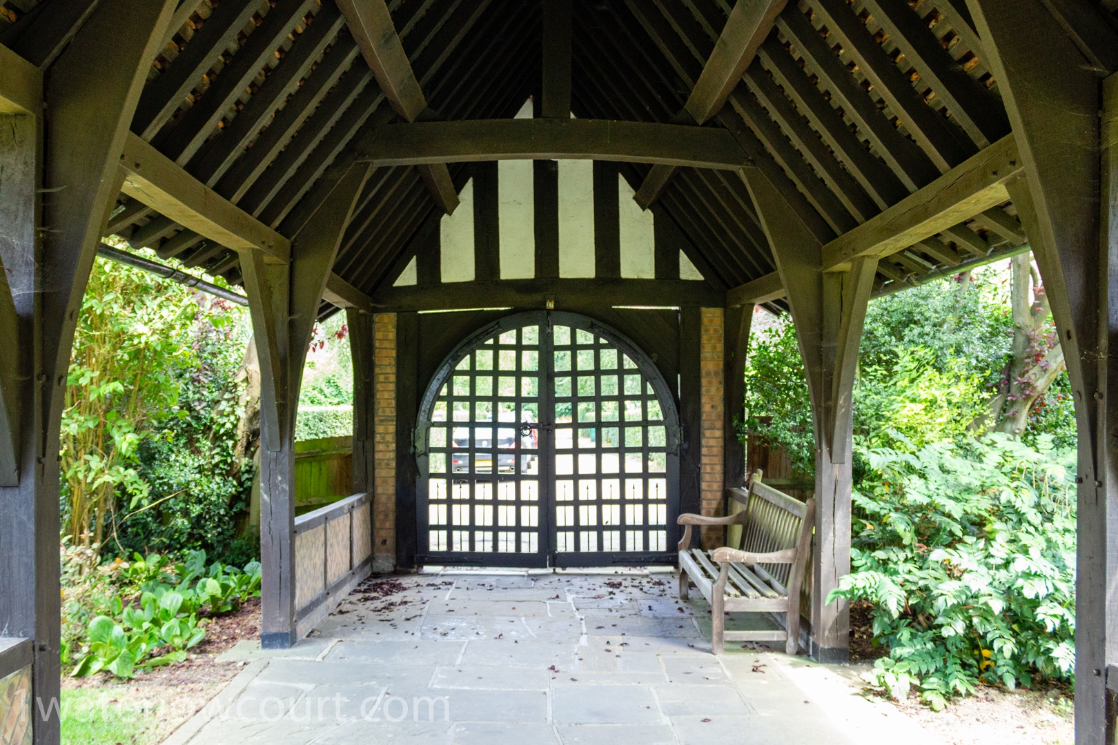 The covered walkway that leads to the timber-framed gate at the entrance of Waterlow Court. Waterlow Court is an Arts & Crafts Grade II* listed building, designed by M. H. Baillie Scott, 1909, located in Hampstead Garden Suburb, London NW11 7DT. Flat 1, a one-bedroom, ground-floor flat, is for sale. Listed on Rightmove and Zoopla.